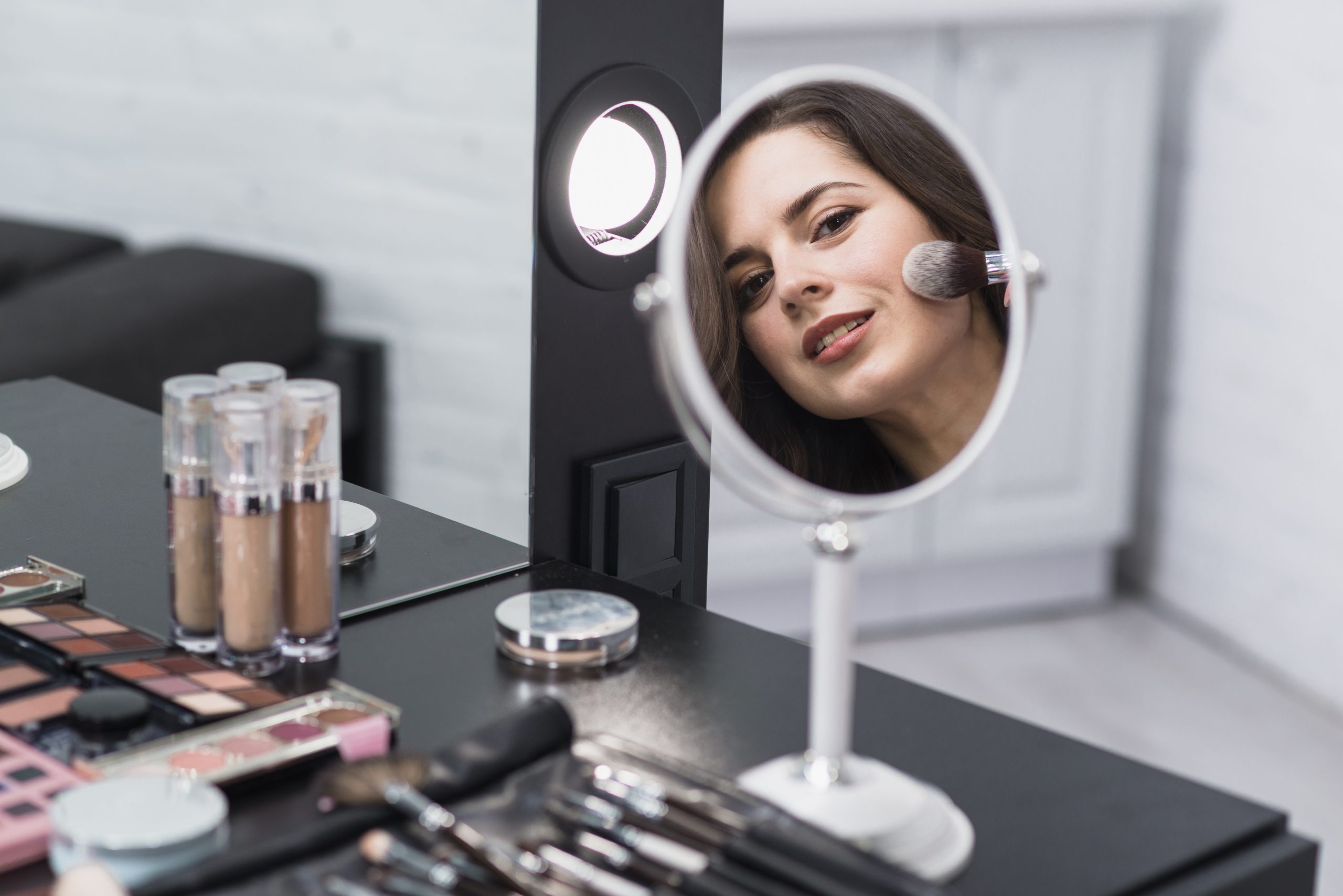 mujer-reflejando-espejo-aplicando-maquillaje-brocha